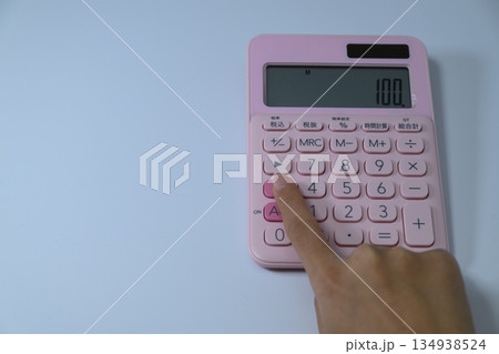 ピンクの電卓を指で操作する女性の手元 ピンクの電卓を指で操作する女性の手元 134938524