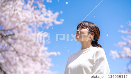 青空に舞い散る桜を見上げる若い女性 高画質 16:9サイズ 134939515