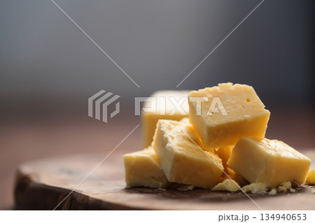 White cheddar cheese pieces on olive wood board White cheddar cheese pieces on olive wood board 134940653