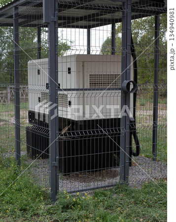 Installation of a large industrial fuel-fired generator on a green lawn. A mobile power source, backup equipment for power plants. Installation of a large industrial fuel-fired generator on a green lawn. A mobile power source, backup equipment for power plants. 134940981