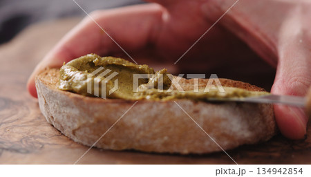 man spread pistachio cream over ciabatta slice closeup 134942854