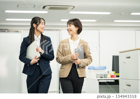 オフィスで同僚と話しながら歩く若いキャリアウーマン 134943318