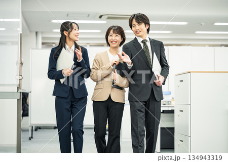 同僚と楽しく話しながら歩く若いビジネスパーソン 同僚と楽しく話しながら歩く若いビジネスパーソン 134943319