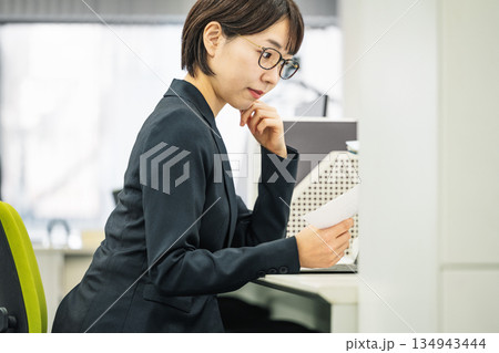 オフィスで書類を見ながら考える若い女性 134943444
