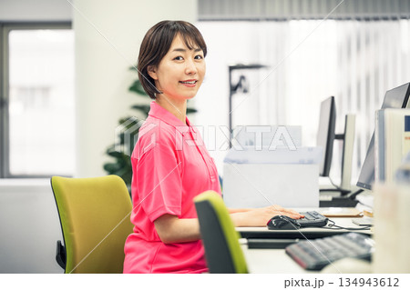 オフィスでデスクワークをするポロシャツ姿の若い女性 134943612