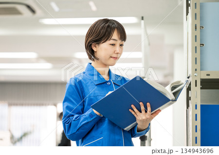 オフィスで資料を見る作業服姿の若い女性 134943696