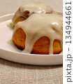 Cinnamon rolls with white icing glaze on a plate. 134944661