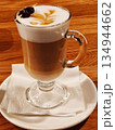 Latte coffee with milk foam art and pine cone garnish in glass. 134944662
