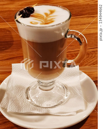 Latte coffee with milk foam art and pine cone garnish in glass. 134944662