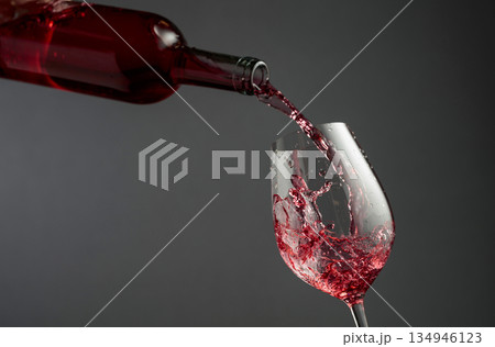 Pouring pink wine from a bottle into a glass. Pouring pink wine from a bottle into a glass. 134946123