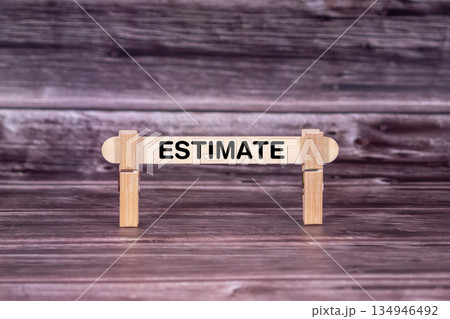 Estimate symbol. Wooden stick held by Clothespins, beautiful Realistic Grunge Wooden Background. Business and Estimate concept with copy space 134946492