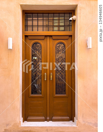 Wooden entrance door with wrought iron details and security camera 134946605
