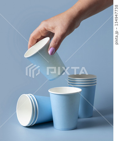 Female hand with disposable light blue paper cup closeup, mockup, copy space. Single-use cup 134947738
