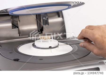 Orthodont men puts tooth implants into dental ceramic oven for baking enamel. Dental prosthetics 134947740