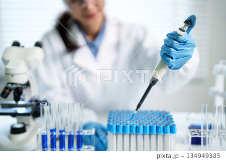 Asian adult scientist researcher experiment liquid pipetting precise accurate work science laboratory medical facility 134949385