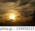 夕焼雲の中を太陽に向かう馬のような形の雲 134950215