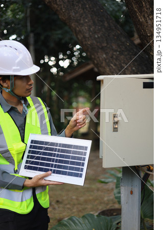 An electrician or solar technician working on an outdoor electrical system involving a solar panel for powering outdoor lights or security systems. An electrician or solar technician working on an outdoor electrical system involving a solar panel for powering outdoor lights or security systems. 134951718