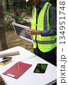 A person in safety gear holding a portable solar panel. 134951748