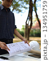 Civil engineer or site manager reviewing construction blueprints outdoors on a construction site. 134951759