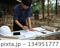 Civil engineer or site manager reviewing construction blueprints outdoors on a construction site. 134951777