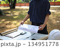 Civil engineer or site manager reviewing construction blueprints outdoors on a construction site. 134951778