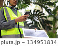 Engineer man wearing a high-visibility safety vest and a hard hat, checking operation of solar panel system with digital tablet or smartphone. 134951834