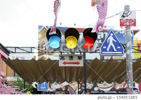 Japanese street traffic light with blue, yellow, and red signals illuminated. Urban scene includes pedestrian crossing sign, Japanese text high-speed train Japanese street traffic light with blue, yellow, and red signals illuminated. Urban scene includes pedestrian crossing sign, Japanese text high-speed train 134951865