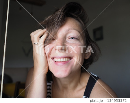Woman Smiling with Hand on Face in Close-Up Portrait 134953372