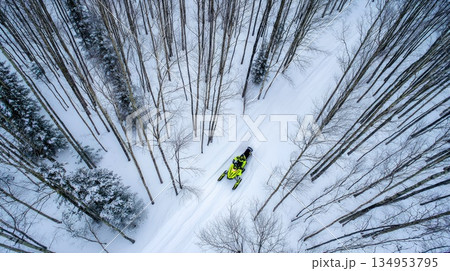 Top View Aerial Shot of Snowmobile Riding Through Winter Forest Trail 134953795