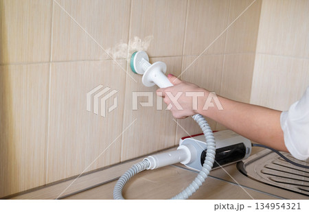 Using a kitchen appliance for cleaning on a cabinet surface in a modern home setup 134954321