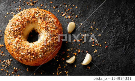 Everything Bagel with Garlic Cloves on Dark Slate Background Everything Bagel with Garlic Cloves on Dark Slate Background 134954331