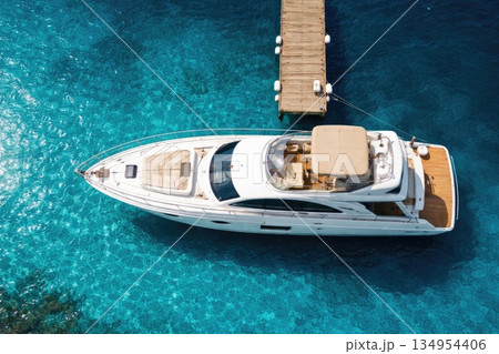 Luxury Motor Yacht Moored at Wooden Pier in Crystal Clear Blue Sea Aerial View 134954406