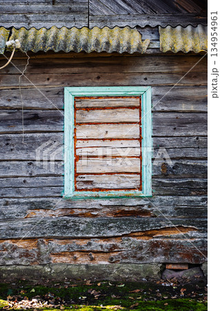 Boarded window of abandoned wooden house with moss growing on wall 134954961