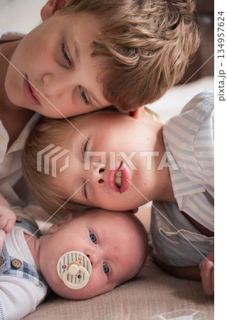 Three brothers lie close together, their heads gently touching, creating a warm and intimate family portrait 134957624
