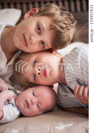 Three brothers lie close together, their heads gently touching, creating a warm and intimate family portrait 134957631