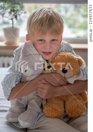 Young boy hugs soft teddy bears at home, portrait with gentle daylight, neutral colors, calm and comforting childhood moment Young boy hugs soft teddy bears at home, portrait with gentle daylight, neutral colors, calm and comforting childhood moment 134957633