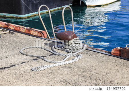 Mooring line on rusty pier bollard referred to a post on a ship or quay. 134957792