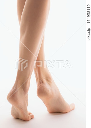 Elegant Woman's Bare Legs and Feet Posing on a White Background 134958119