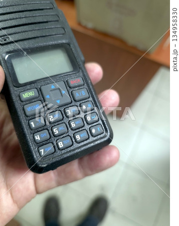 Person Holds Walkie Talkie While Inside a Room During Daytime Activity Person Holds Walkie Talkie While Inside a Room During Daytime Activity 134958330