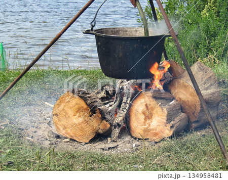 A large pot is on a tripod over a fire A large pot is on a tripod over a fire 134958481