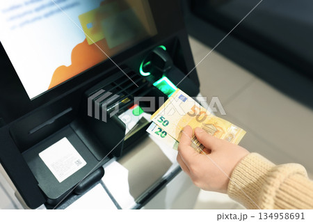 Woman holding Euro banknotes at ATM. Hand with 50 and 20 euro cash near bank terminal close up. High quality photo 134958691