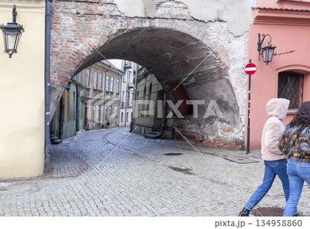 Ancient stone arch of a building in the center of Lublin, a lantern on the red wall Ancient stone arch of a building in the center of Lublin, a lantern on the red wall 134958860