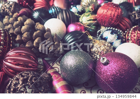 Colorful decorations fill the scene, capturing the joy of Christmas and New Year celebrations. Shiny ornaments and pinecones create a lively and cozy atmosphere, inviting warmth and cheer Colorful decorations fill the scene, capturing the joy of Christmas and New Year celebrations. Shiny ornaments and pinecones create a lively and cozy atmosphere, inviting warmth and cheer 134959844