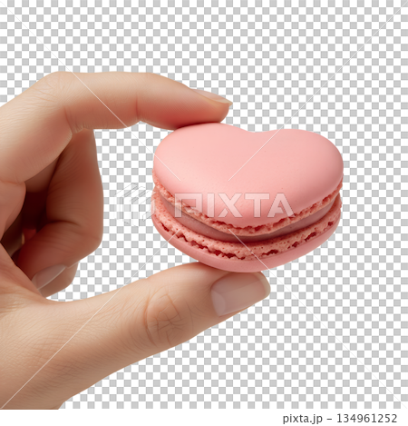 Delicate pink heart-shaped french macaron held carefully in a hand, representing elegant desserts, valentine's gifts, and patisserie art 134961252