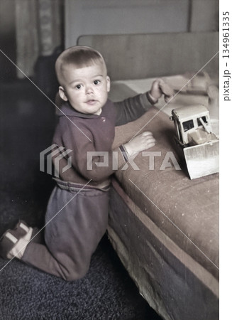 Vintage portrait of little boy playing with toy cars in living room. Funny photo of cute boy. Retro photo from the 1970s. Vintage portrait of little boy playing with toy cars in living room. Funny photo of cute boy. Retro photo from the 1970s. 134961335