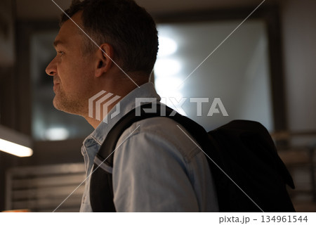 Man standing in bakery with backpack and thoughtful look 134961544