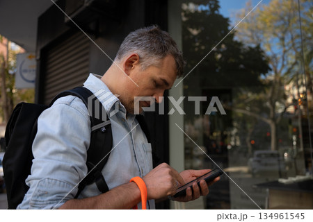 Man using smartphone on city street 134961545