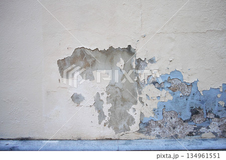 Peeling plaster wall revealing weathered paint and surface layers 134961551