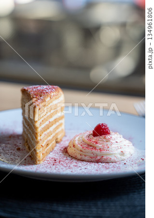 Slice of layered cake with cream and raspberry 134961806
