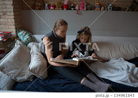 Mother and daughter reading together at home 134961843